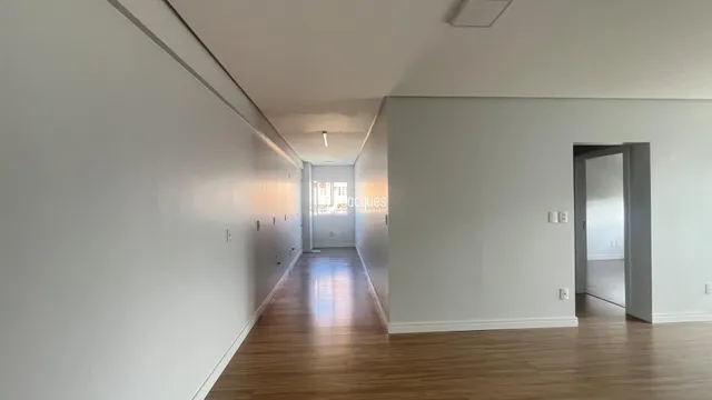 Corredor interno de uma residência com piso de madeira e paredes brancas.