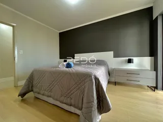 Quarto com cama grande e paredes cinzas.