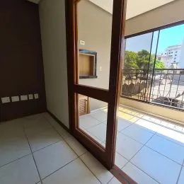 Vista de um interior com piso de cerâmica e porta de madeira que dá acesso a uma área externa.