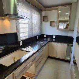 Foto de uma cozinha com bancadas escuras e armários claros.
