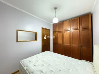 Quarto com armário de madeira e espelho na parede.
