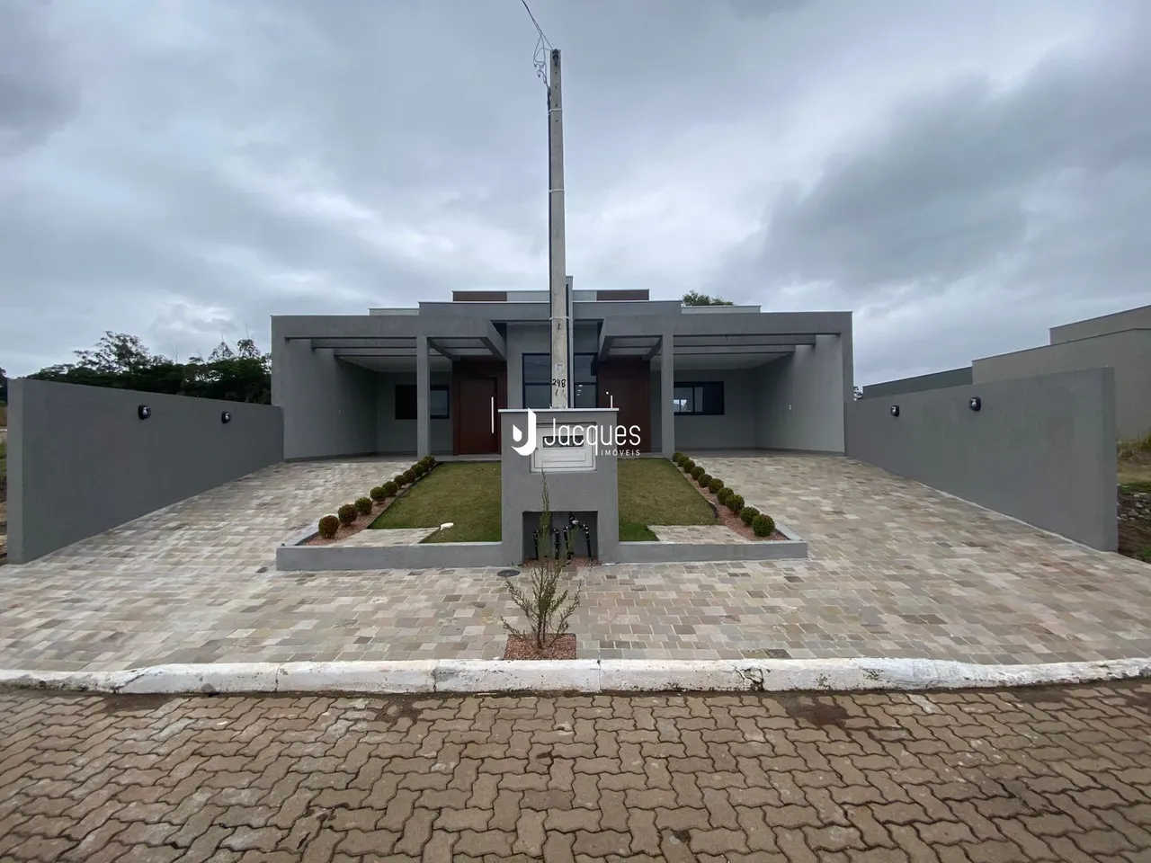Fachada de uma residência moderna com jardim e área pavimentada em Lajeado.