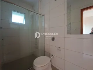 Banheiro com revestimento cerâmico e box de vidro.