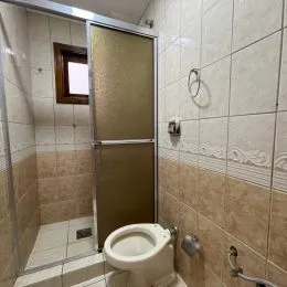 Banheiro com revestimento de azulejos claros e vaso sanitário branco.