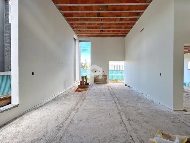 Vista interna de um ambiente em construção com paredes brancas e teto de tijolos expostos.
