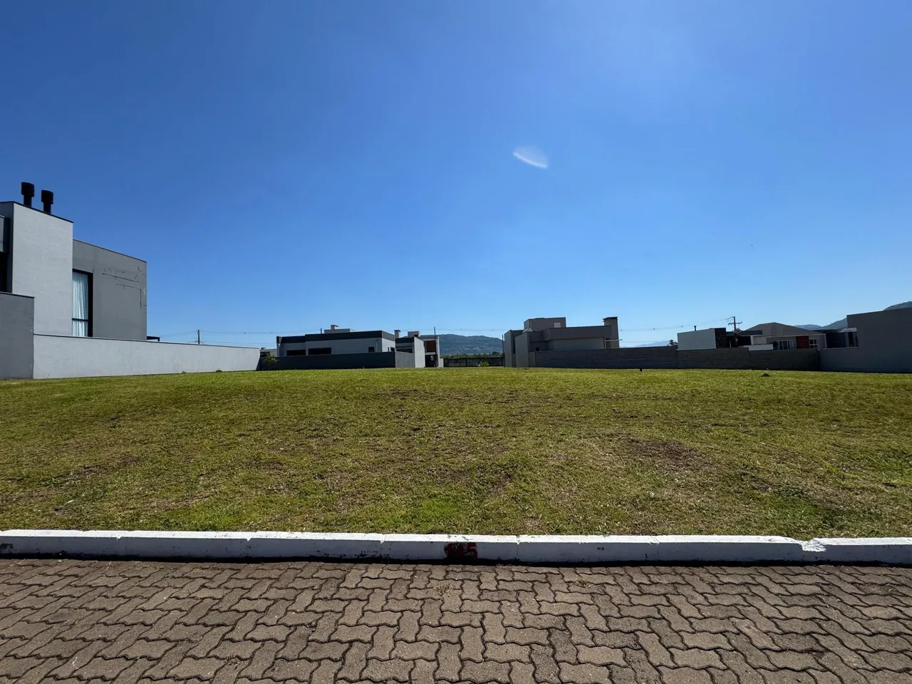 Fachada de uma residência com um grande gramado verde sob um céu azul.
