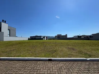 Fachada de uma residência com um grande gramado verde sob um céu azul.