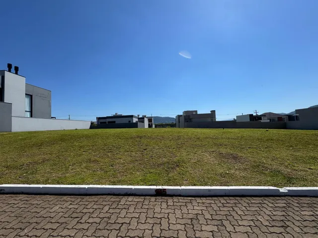 Fachada de uma residência com um grande gramado verde sob um céu azul.