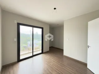 Interior de uma sala com piso de madeira e grande janela.