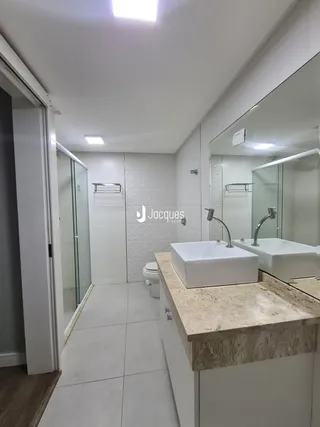 Banheiro moderno com bancadas de mármore e box de vidro.