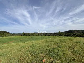 Campo verde extenso com paisagem de colinas ao fundo.