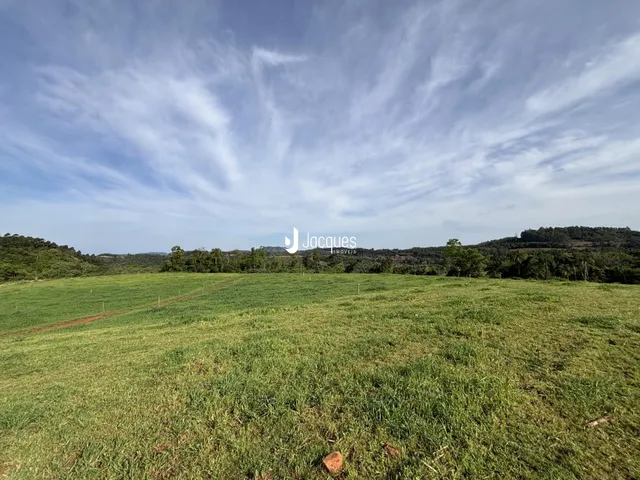 Campo verde extenso com paisagem de colinas ao fundo.