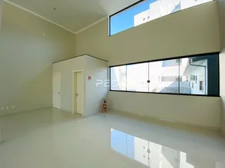 Interior de uma sala ampla com paredes brancas e piso claro.