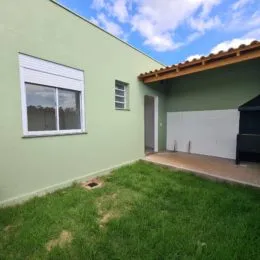 Fachada externa de uma residência com parede verde e gramado na frente.