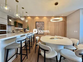 Uma sala de jantar moderna com ilha e cadeiras brancas em um ambiente bem iluminado.