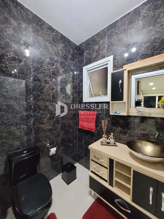 Banheiro com revestimento de azulejo escuro e louças modernas.