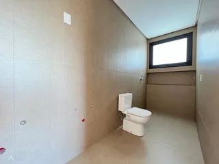 Foto de um banheiro interno mostrando um vaso sanitário branco e paredes claras.