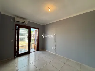 Ambiente interno com piso de cerâmica e porta de vidro que dá acesso ao exterior.