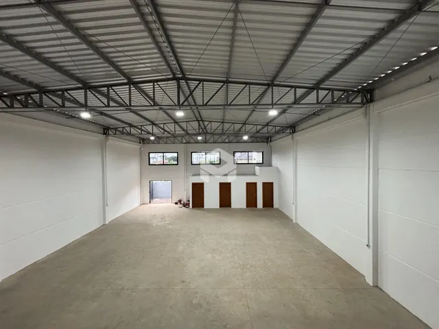 Espaço interno amplo com teto de estrutura metálica e piso de concreto.
