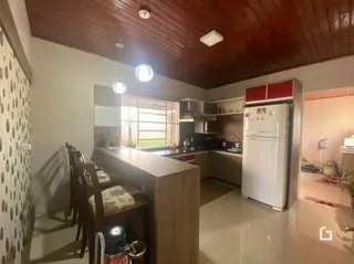 Sala com teto de madeira e piso claro na residência.