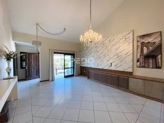 Sala de estar ampla com piso de cerâmica branca e parede de mármore.