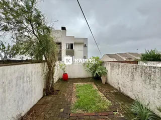 Vista externa de um pátio com gramado e muro branco em uma propriedade em Lajeado.