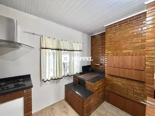 Cozinha com bancadas escuras e parede de tijolos aparentes.