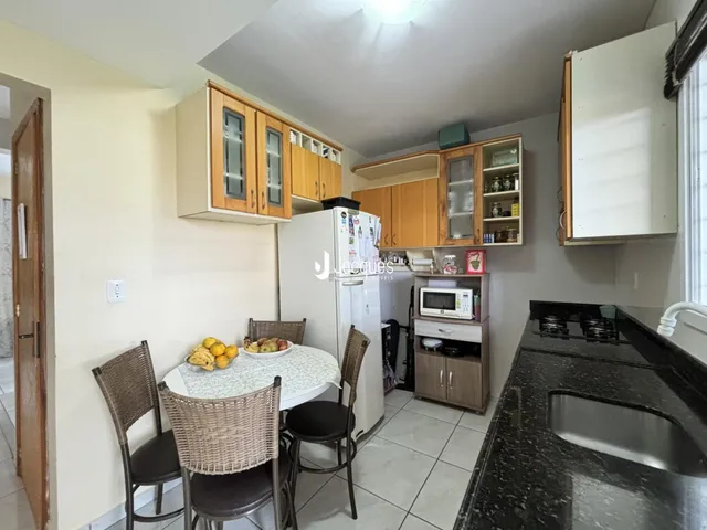 A cozinha e a área de jantar mostram armários de madeira e uma mesa de jantar.