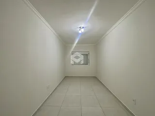 Uma sala de estar vazia com piso de cerâmica e paredes brancas.