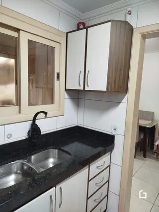 Uma cozinha com armários brancos e bancada escura.