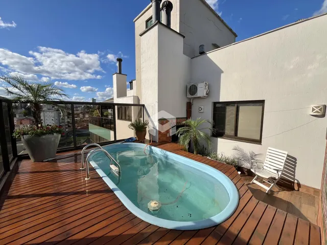 Vista de uma área externa com jacuzzi em deck de madeira.
