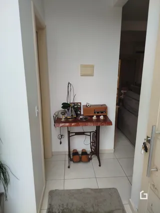 Hall de entrada de uma residência com paredes brancas e piso claro.