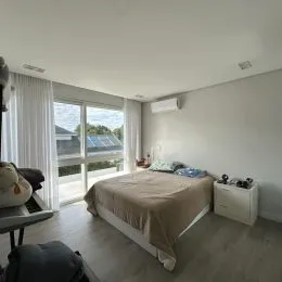 Quarto com cama e grandes janelas de vidro.