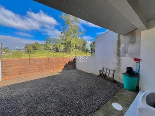 Área externa com piso de cascalho e muro de tijolos no imóvel.