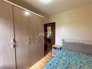 Quarto com armários em madeira e cama no interior da residência.