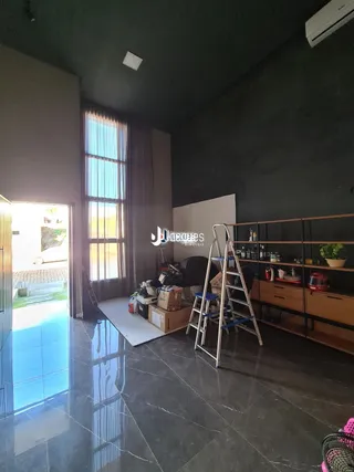 Interior de uma sala com grande janela e piso de pedra escura.