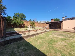 Vista externa de um terreno com gramado e muro de tijolos