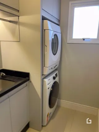 Vista de parte da cozinha com armários brancos e máquinas de lavar.