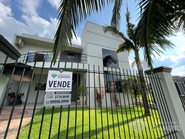 Fachada de uma residência moderna em Lajeado, Brasil, com cerca de ferro e jardim.