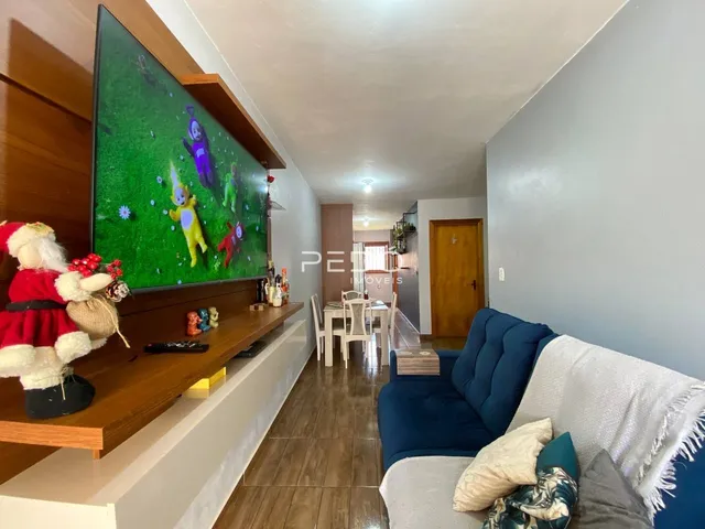 Sala de estar com sofá azul e televisão montada na parede.
