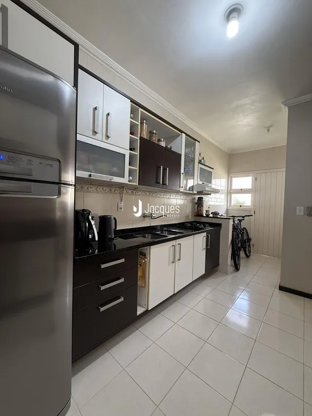 Foto da cozinha com armários escuros e bancadas pretas.