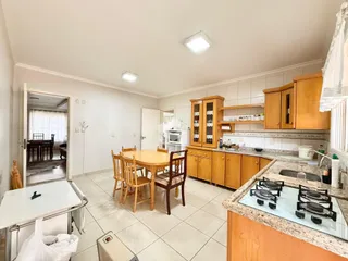 Sala de jantar com mesa de madeira e cozinha integrada.