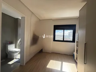 Interior de um ambiente com piso de madeira e porta de acesso a um banheiro.