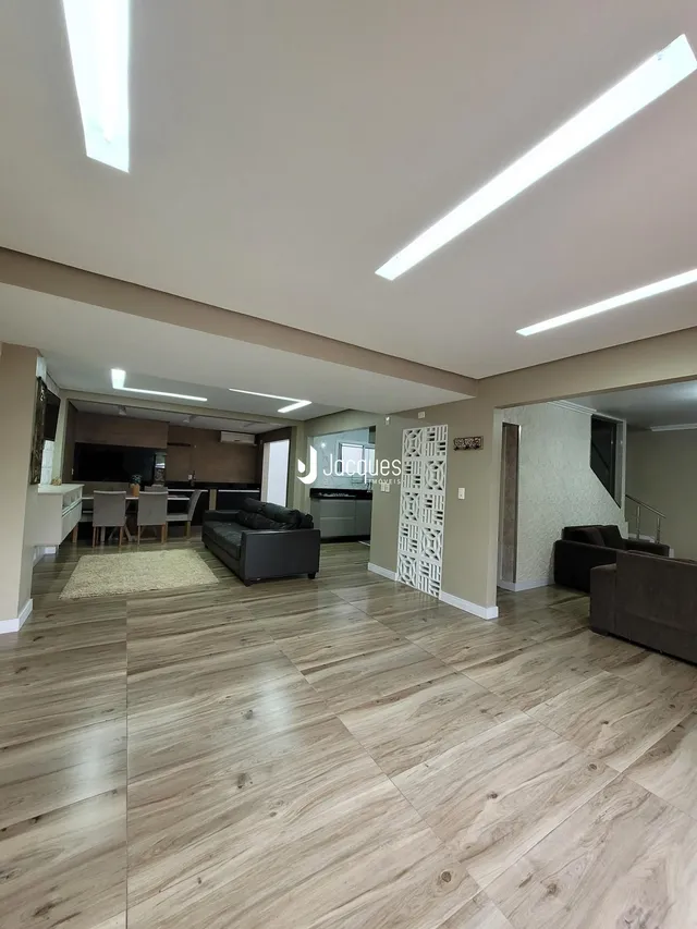 Sala de estar com piso de madeira e ambiente aberto em Lajeado.