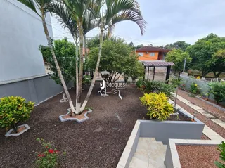 Vista externa de um jardim com árvores e área de terra batida.