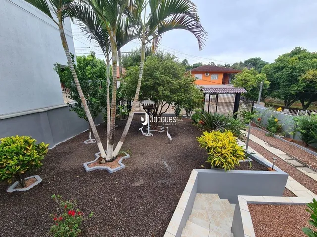 Vista externa de um jardim com árvores e área de terra batida.