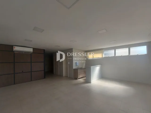 Interior de uma sala ampla com armários em madeira e iluminação moderna.