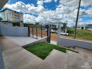 Vista externa de uma propriedade com muro baixo e área gramada.