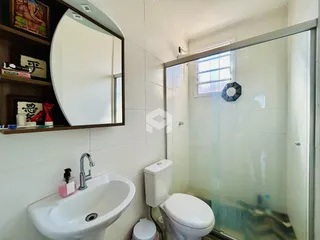 Interior de um banheiro com azulejos brancos e box de vidro.