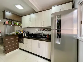 Vista da cozinha moderna com armários brancos e bancadas escuras.